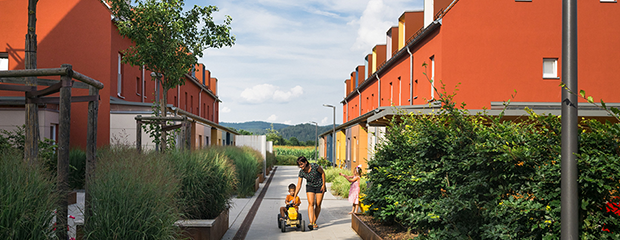 Kinder spielen mit ihrer Mutter in den barrierefrei gestalteten Freianlagen eines Wohnquartiers in Regenstauf.